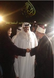 Syech Yusuf al-Qardhawi salaman dengan istri Emir Qatar, disaksikan Sang Emir yang tersenyum.
