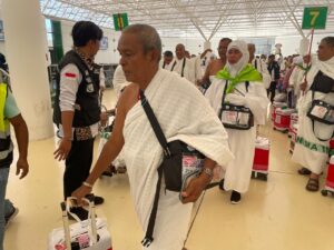 Seorang petugas haji membantu memeriksa ihram jemaah. (Alvin-islamidotco/MCH 2024)